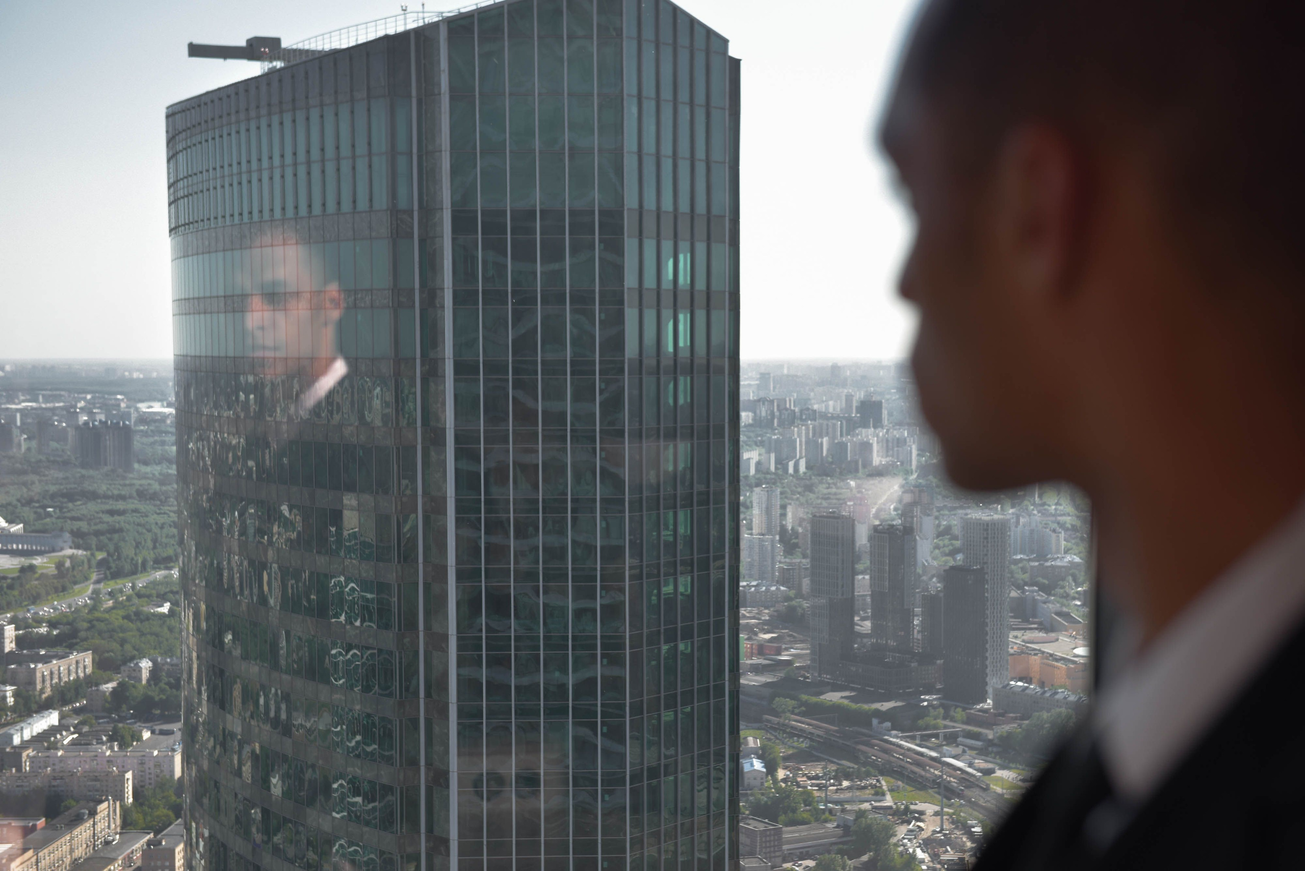 Executivo observando uma cidade por uma janela durante o nascer do sol